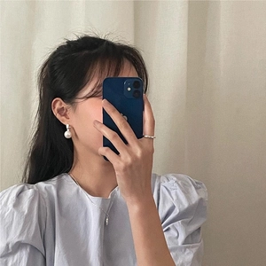 Mirror selfie showing pearl earrings, silver chain necklace and ring on a model