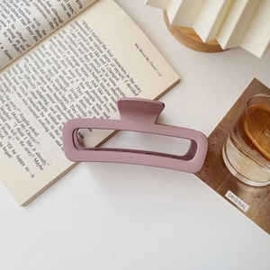 Dettaglio molletta per capelli rettangolare lilla opaca su scrivania con libri