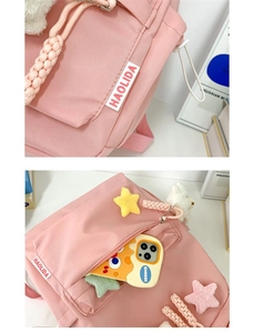 Detailed close-up of pink backpack featuring cute plush pendants and brand label detail