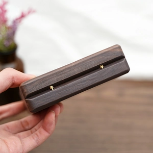 Macro view of compact dark wood jewelry box with elegant brass hinges and natural wood grain