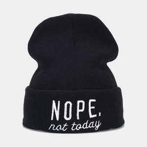 Detail of black knit beanie with white NOPE. not today embroidery on the folded cuff