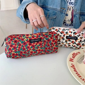 Floral corduroy stationery cases with zippers and brand labels in a lifestyle setting