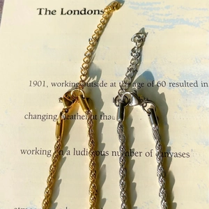 Dettaglio di catene a corda oro e argento con chiusura a moschettone su un libro
