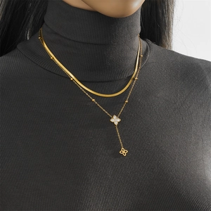 Détail d'un collier double épaisseur en titane doré avec pendentif trèfle sur mannequin