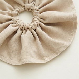 Close-up of khaki oversized fabric scrunchie featuring textured linen and white edge stitching
