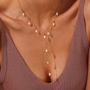Vue détaillée d'un collier en Y en acier inoxydable doré avec pompons de perles élégants