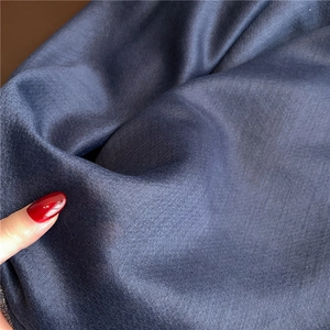 Primer plano de suave tela de bufanda azul oscuro con textura de seda dorada brillante