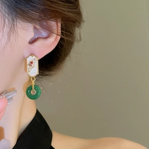 Detail of elegant gold-plated water drop earrings with green and white glaze on a model