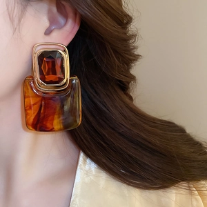 Detail of amber resin geometric earrings on model showing vintage gold hardware