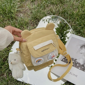 Cute yellow canvas shoulder bag with bear ears and clear pocket on green grass