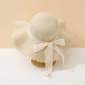 Detail of the white lace bow and wavy edge on this beige straw sun hat for women