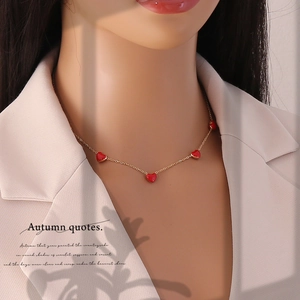 Elegant gold chain necklace with multiple red heart pendants worn by a female model