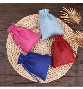 Colorful linen drawstring bags for jewelry storage on a natural woven mat backdrop