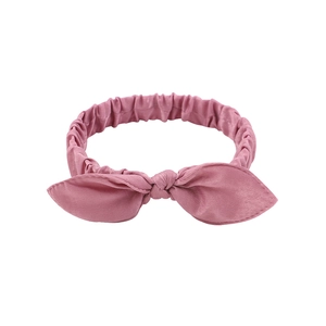 Close-up of pink cotton fabric baby headband with elastic knot and rabbit ear design