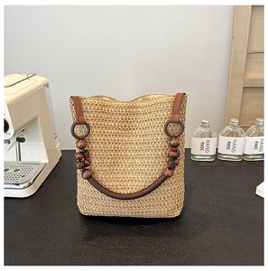 Detail of hand-woven straw tote with vintage dark brown wooden bead handles on a table