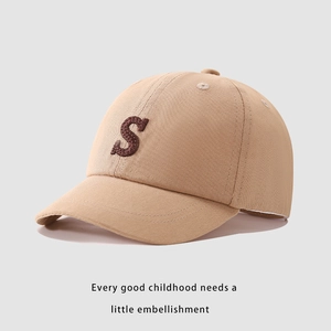 Dettaglio del cappellino in cotone kaki con lettera S ricamata e occhielli traspiranti