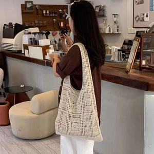 Close-up of beige crochet hollow-out knit tote bag with geometric pattern in cafe setting