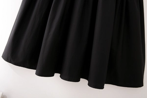 Détail d'une robe midi noire en coton avec ourlet plissé élégant et tissu tissé lisse