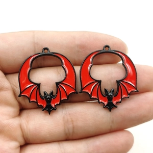 Vue détaillée de deux breloques chauve-souris vintage avec émail rouge et cadre en métal