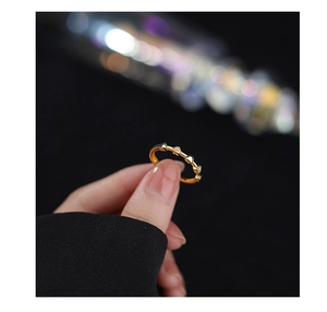 Detailed close-up of golden braided heart ring with sparkling zircons held by hand