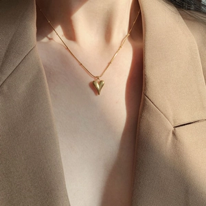 Elegant gold heart pendant necklace for women on minimalist bead chain with warm natural light