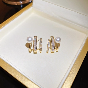 Macro detail of gold-plated claw earrings with elegant pearls and sparkling zircons