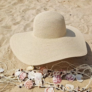 Detailed texture of hand-woven straw beach hat with decorative seashell ornaments