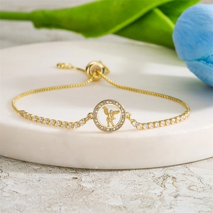 Close-up of golden tennis bracelet featuring a cupid angel pendant on marble