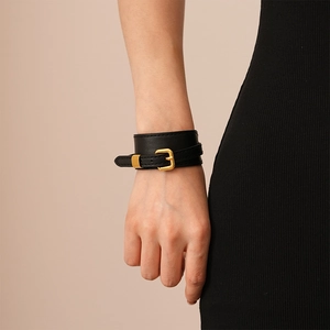Close-up of black faux leather buckle bracelet with golden adjustable metal buckle