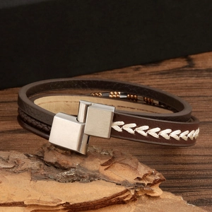 Detail of multilayer brown leather bracelet with geometric metal clasp and woven texture