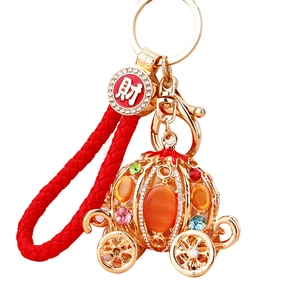 Golden pumpkin carriage keychain with colorful rhinestones and red braided rope
