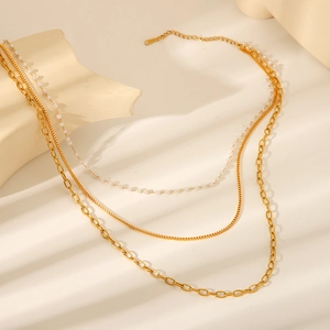 Detail of layered 18K gold plated necklace with pearl, snake chain and paperclip links