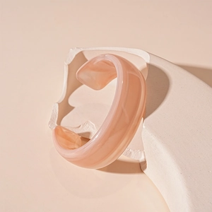 Macro view of wide acrylic bangle featuring a translucent apricot marble texture