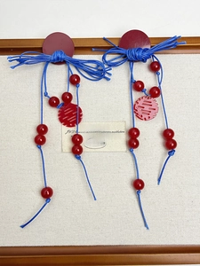 Detail of blue tassels and red Double Happiness charms on festive Chinese style earrings