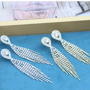 Close-up of elegant long tassel earrings with sparkling rhinestones in gold and silver