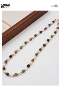 Close-up of mixed freshwater pearls and colorful stone beads on a gold-accented necklace