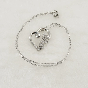 Close-up of silver heart necklace with LOVE engraving and diamonds on white fur