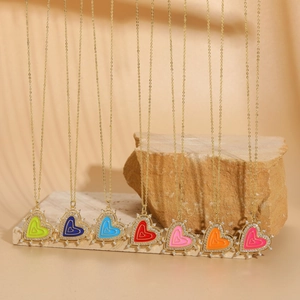 Colorful heart drip oil zircon necklaces with gold chains displayed on natural stones