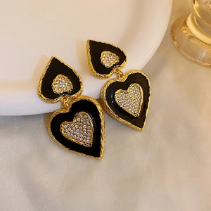 Detailed shot of vintage gold heart earrings with black enamel and sparkling rhinestones