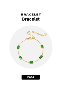 Detail of gold chain bracelet featuring five rectangular emerald green stones and logo tag