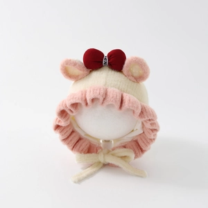 Detailed close-up of knitted baby earflap hat with pink bow and ruffled edges