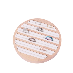 Close-up of circular solid wood ring display tray with white padded slots and six rings