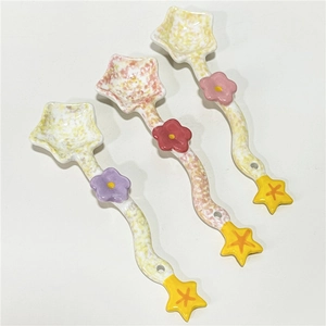 Three colorful star-shaped ceramic spoons with floral pattern and spotted glaze finish