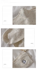 Close-up of cream knit socks featuring colorful flecks and a cute sheep embroidery detail