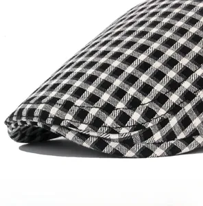Close-up of a black and white plaid beret showing the crisp brim and woven fabric texture