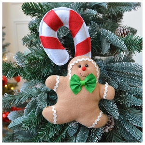 Close-up of a plush felt gingerbread man ornament with candy cane on a Christmas tree