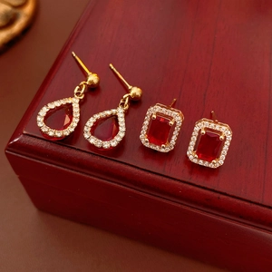 Macro shot of gold square and teardrop earrings with red gemstones and crystals