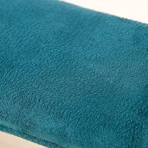 Macro shot of the peacock blue velvet fabric texture on the wooden jewelry display stand