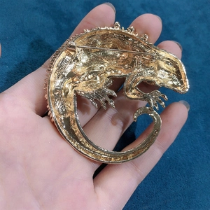 Back view of a large gold lizard brooch with scale texture and secure safety pin clasp