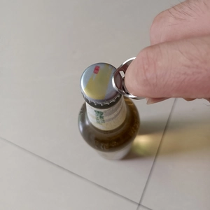 Action shot of silver stainless steel ring bottle opener being used on a beer bottle